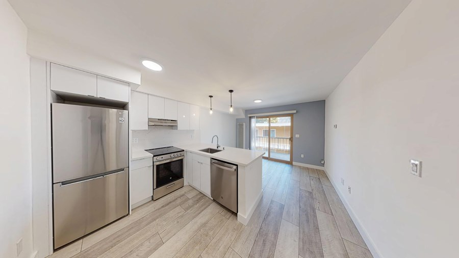 A modern kitchen with stainless steel appliances and wooden flooring.